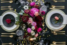 03 a black and gold NYE table setting with gold chargers and cutlery, gold candleholders, bright blooms and gold and silver sequins on the table