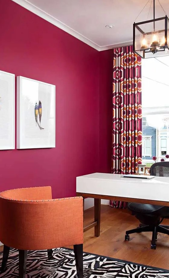 a magenta home office, a white desk, a black chair, an orange one, a printed rug and crutains for a bold look