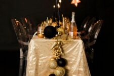 04 a black and gold NYE tablescape with a large ornament and star runner, black candles and lots of black glitter
