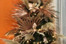 05 a Christmas tree with fronds, pampas grass, fabric blooms and lights plus gilded leaves is a cool idea for a tropical holiday space
