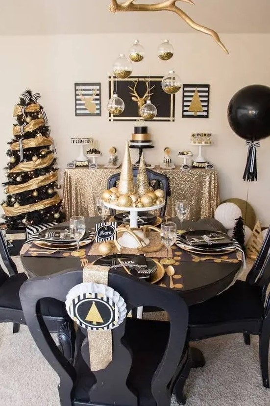 a black and gold tablescape with shiny and glitter ornaments and cone trees, black plates and chargers