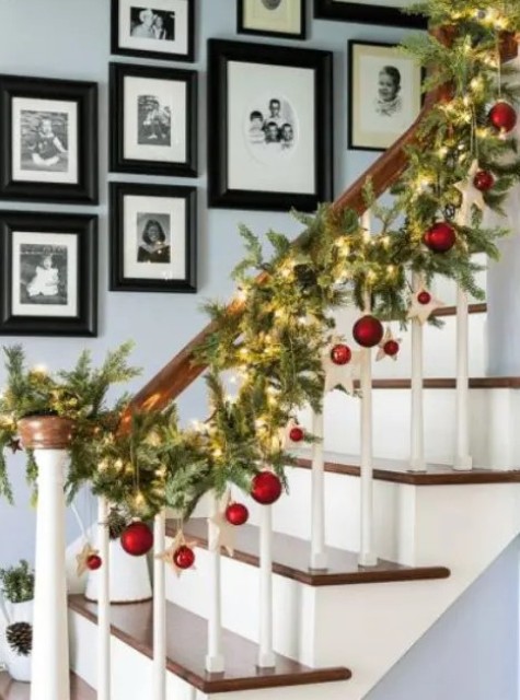 a fir Christmas garland with lights and red ornaments hanging is a beautiful idea for Christmas banister decor