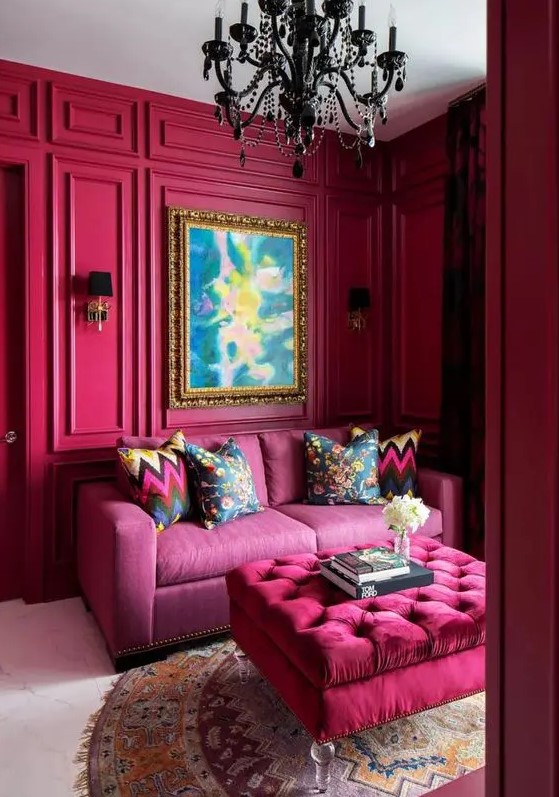 a magenta space with a pink sofa, a hot pink ottoman, a black crystal chandelier and a statement artwork is amazing