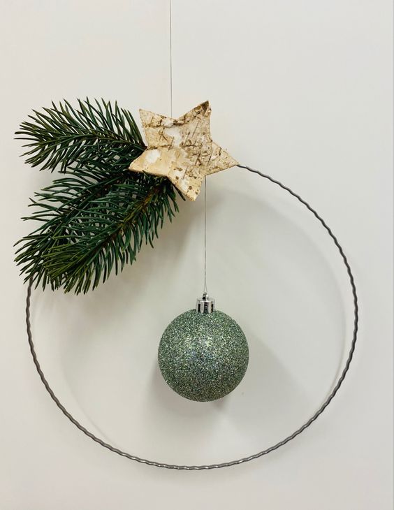 a minimalist Christmas wreath with evergreens, a bark star, a green glitter ornament is a creative and cool idea