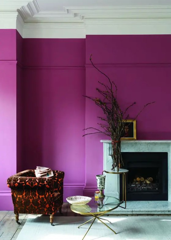 a magenta to hot pink space with a fireplace, a bold printed chair, a couple of coffee tables and some branches plus artwork