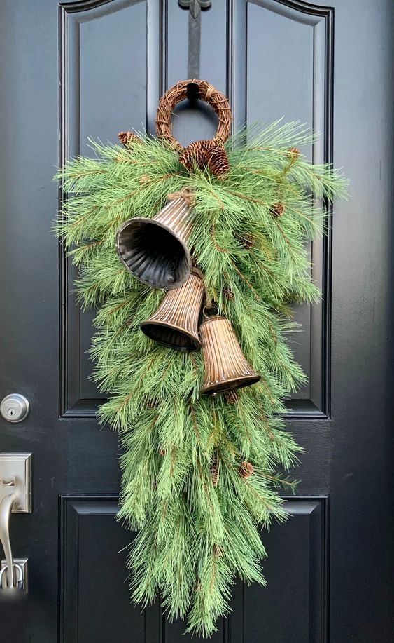 a super lush green Christmas posie with large vintage bells and pinecones is a lovely vintage decor idea for the front door
