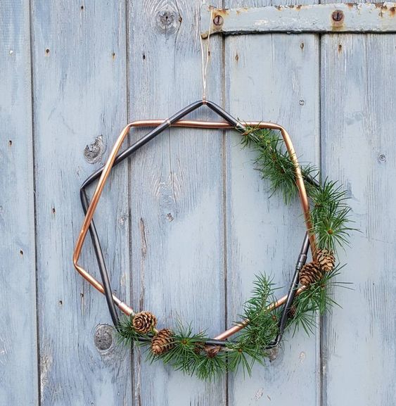 a geometric Christmas wreath with greenery and pinecones is a stylish and modern decor idea for the holidays