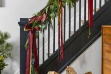 09 a greenery garland with leaves and bold red ribbon bows is a bold and cool decor idea for Christmas