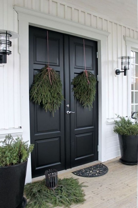 all-natural Christmas front door decor with evergreen swags, some evergreens on the floor and in pots