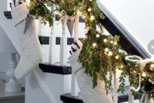 10 a greenery garland with lights, paper cones, large white stockings is a lovely piece to decorate railing for Christmas
