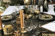 11 a chic black and gold NYE party tablescape with black table runners and placemats, black and gold plates, gold candles and candleholders