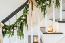 11 a lovely evergreen garland with silver ornaments and elegant tan bows plus candle lanterns are great for Christmas