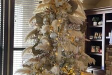 11 a pampas grass Christmas tree decorated with large metallic ornaments, lights and fronds and topped with some branches