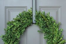 12 a catchy modern Christmas wreath of boxwood, with a striped ribbon will match many styles and decor themes