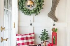 12 a large greenery wreath with a bell and a plaid stocking with evergreens and berries hanging on hooks