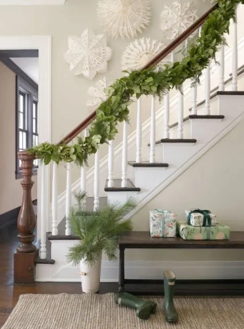 a lush and textural greenery garland on the railing and some branches in a vase are a nice combo for natural Christmas decor