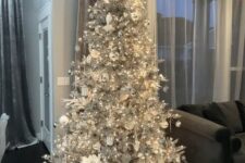 12 a silver Christmas tree with lights, white and silver ornaments, fabric blooms and silver gift boxes is a stylish and bold idea