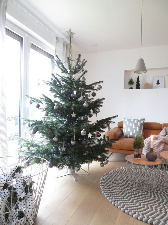 a Christmas tree decorated with black, grey and white baubles and stars is a stylish idea for a Scandi space