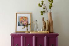 13 a beautiful magenta cabinet with vintage ring handles, greenery, wooden vases, art and gold touches is a bold and cool decor piece