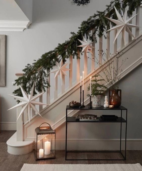 a lush evergreen garland paired with white paper stars is a stylish and bold decor idea for Christmas