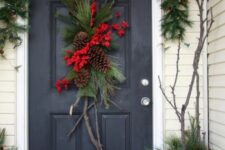 13 an evergreen swag with branches, pinecones and red blooms plus an evergreen garland with lights over the door for Christmas