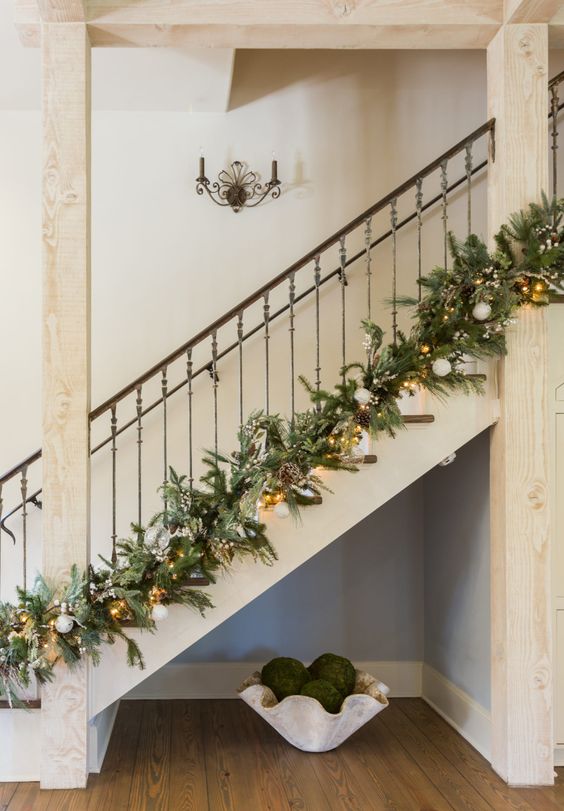 a pretty Christmas garland of evergreens, pinecones and white ornaments, lights and leaves to decorate the lower part of the banister