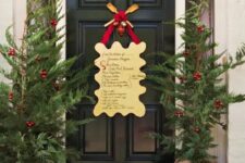 16 a Christmas front door with an artwork with song lyrics, Christmas trees with red ornaments and blooms in burlap