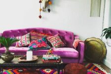 16 a bright boho living room with a fuchsia sofa and bold pillows, a bright printed rug, a coffee table, leather poufs and some boho decor