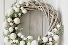 17 a creative whitewashed vine Christmas wreath decorated with greenery and wite ornaments is a cool Scandi decor