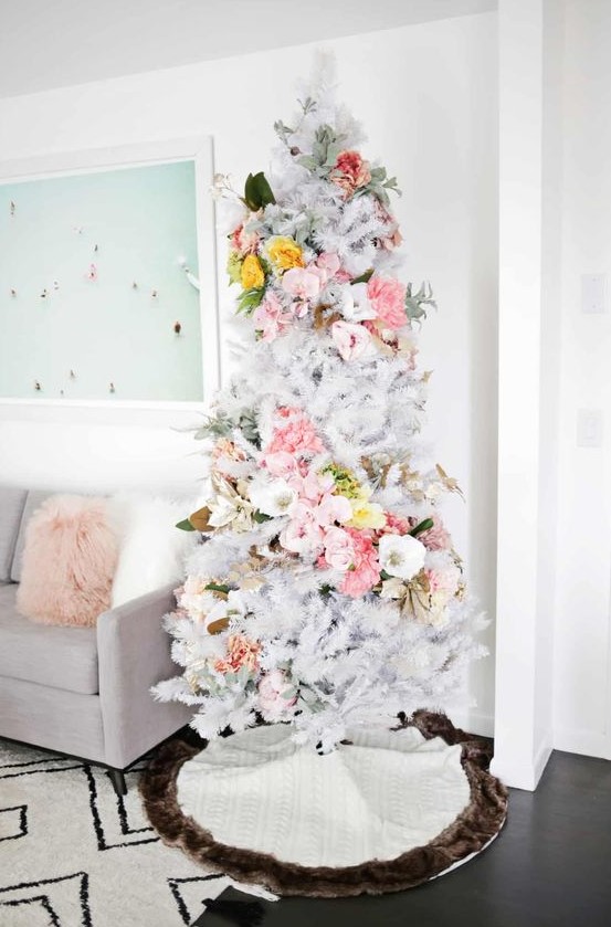 a delicate white Christmas tree with pink, white and yellow florals covering it in a swirl, with pale greenery is an out of the box idea