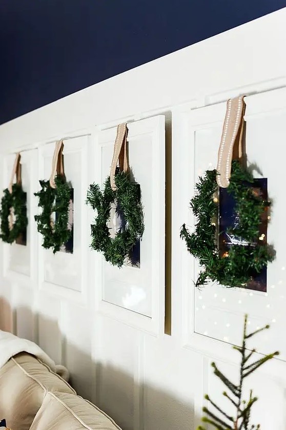 family photos hanging on the wall are covered with greenery wreaths and ribbons for a festive feel
