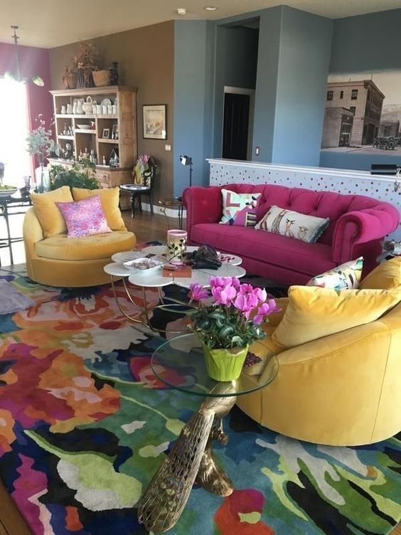 a bright living room with a magenta sofa and yellow chairs, a bright rug, a glass and flower-shaped table