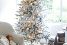 18 a flocked Christmas tree decorated with only lights and white silver and white ribbons is a cool and fresh idea
