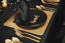 18 a minimal black and gold NYE party table with gold placemats and cutlery, gold candleholders and black napkins is wow