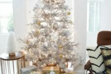 metallic decor ideas – a silver tree with gold and white ornaments and gift boxes wrapped with gold and silver