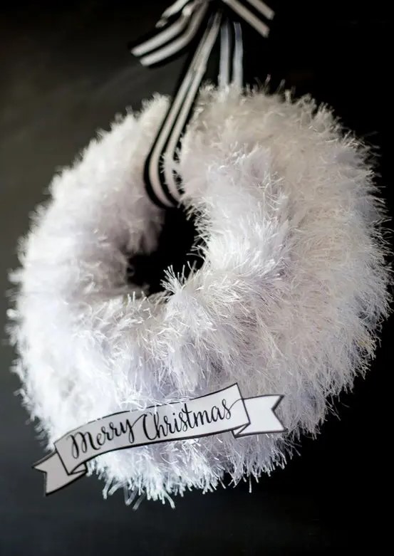 a fluffy white wreath with a striped ribbon and a black and white paper note is a cool idea for a modern Christmas space