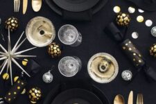 19 a modern black and gold NYE party tablescape with black plates, gold and black ornaments, a large star and disco balls