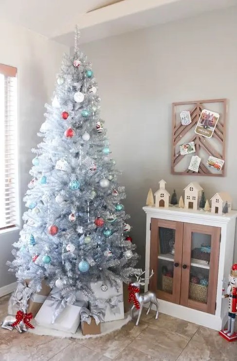 a vintage silver Christmas tree with blue, white and red ornaments and stacks of gift boxes and deer is a beautiful and refined idea