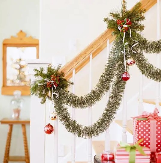 an elegant tinsel garland with gold and red ornaments, evergreens and berries are a nice combo for Christmas decor