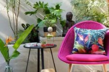 20 a cool outdoor nook with a woven magenta chair, a side table, a cushion, potted plants and beautiful Asian-inspired decor