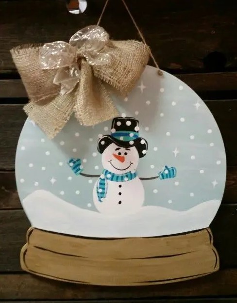 a snow globe door hanger with a burlap bow is a cool and fun decor idea for a front door at Christmas