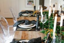 21 a pretty NYE tablescape with black placemats and printed black napkins, a greenery runner with LEd lights and champagne bottles
