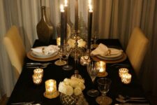 22 a refined black and gold NYE party tablescape with white roses, a bottlebrush tree, black candles and white porcelain plus gold candleholders