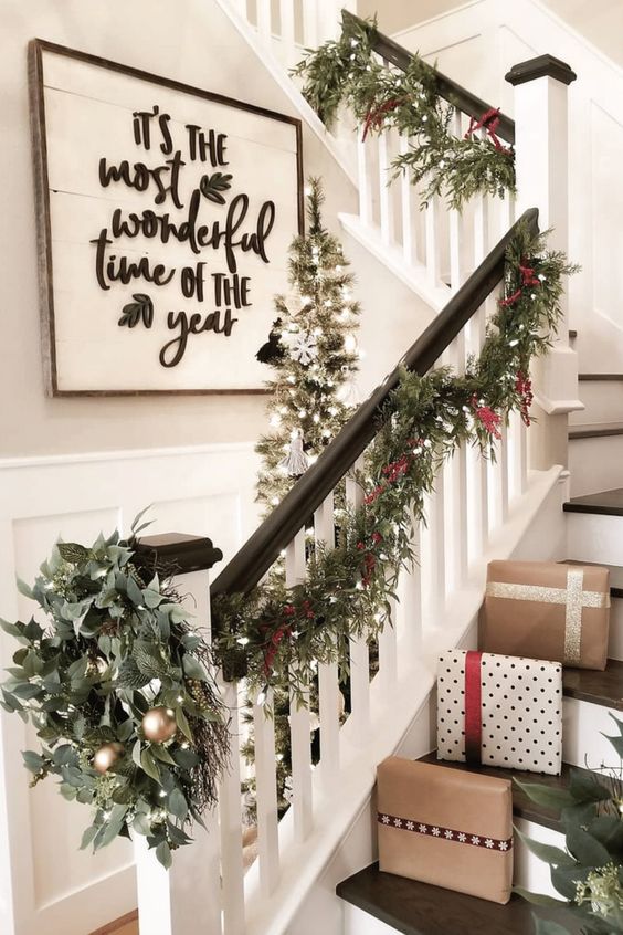 an evergreen Christmas garland with berries and lights, a matching wreath with gold ornaments for banister decor