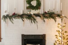 23 a boho Christmas mantel decorated with greenery, pampas grass and bold blooms, tall and thin candles and an evergreen wreath on the mirror