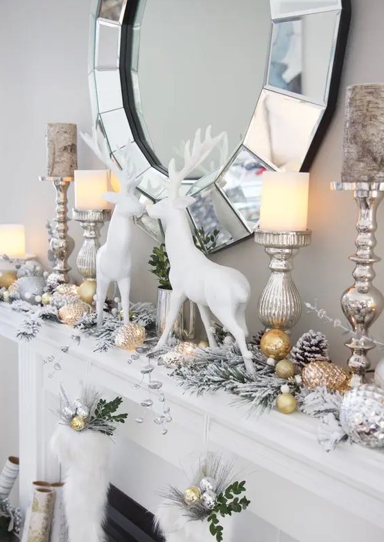 a glam Christmas mantel with snowy evergreens, gold and silver ornaments, white deer and some stockings