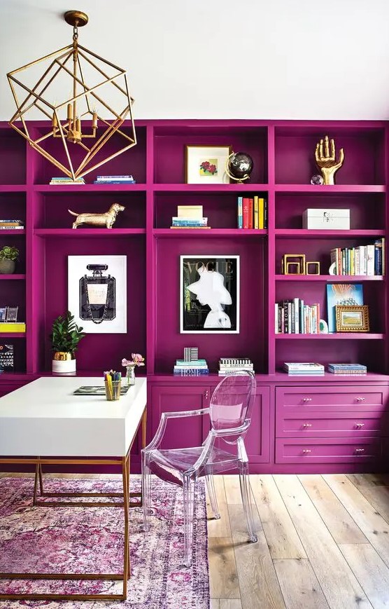 a jaw-dropping home office with a magenta storage unit that creates an ambience, a white desk and a clear chair, a gold chandelier