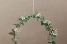 23 a modern and delicate Christmas wreath with a bit of foliage, baby’s breath and a small lit up house is amazing