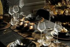 23 a shiny black and gold Christmas tablescape with leaves printed, gold chargers and black plates, candles and an ornament stand
