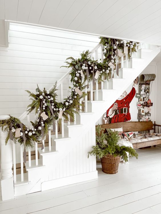 an evergreen Christmas garland with cards, silver ornaments and black ribbon bows is a cool way to style a banister